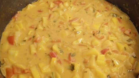 Ein kräftiges vegetarisches Curry köchelt in einer Pfanne, umgeben von einer modernen Küchenumgebung.