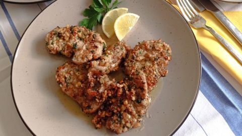 Putenschnitzel liegen auf einem Teller mit Walnusskruste und sind mit Zitronenscheiben und Petersilie garniert, umgeben von frischem Salat.
