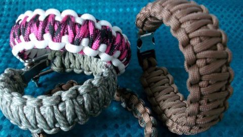 Bunte Paracord-Armbänder liegen auf einem blauen Hintergrund, bereit zum Tragen oder zur Verwendung.