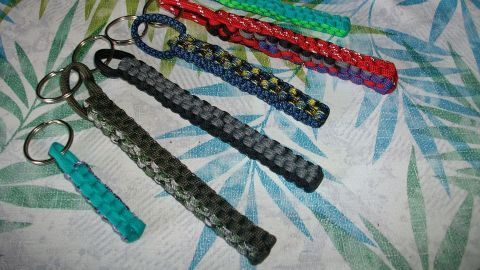 Bunte Lanyards aus Paracord liegen auf einem blumigen Stoff, die Schlüsselringe sind zum Befestigen geeignet.