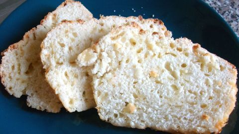 Schnelle, goldbraune Käsebrot-Scheiben liegen auf einem blauen Teller, umgeben von einer modernen Kücheneinrichtung.