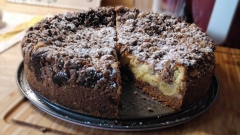 Ein leckerer Schwarz-Weiß-Quarkkuchen mit Streuseln, frisch angeschnitten, auf einem silbernen Teller in moderner Küche.
