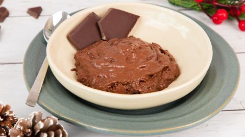 Eine cremige Schokocreme in einer Schüssel, umgeben von Schokoladentafeln und dekorativem, festlichem Umfeld.