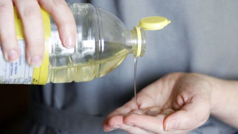 Wenn du deine Hände vor dem Teig kneten etwas einölst, so bleibt der Teig nicht an den Händen kleben. Eine Hand gießt Öl aus einer Flasche in die andere Hand, um zu verhindern, dass der Teig kleben bleibt.