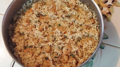 Eine große Pfanne mit Cajun-Garnelen-Reis steht auf einem bunten Fliesenmuster, reichlich gefüllt und dampfend.