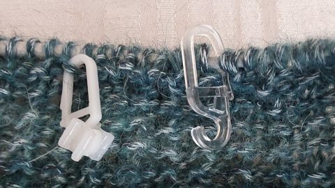 Zwei Gardinenaufhänger halten Maschen in einem blauen Strickstück, ideal als alternative Maschenmarkierer im Handarbeitsprojekt.