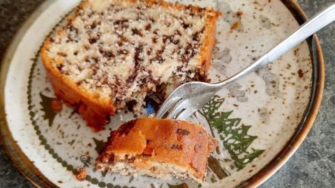 Saftiger Ameisenkuchen liegt auf einem Teller, während ein Stück mit einer Gabel herausgenommen wird.