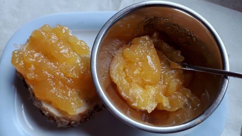 Ein glossy Orangengelee mit Ingwer und Zimt liegt auf einer Brotscheibe, daneben ein Schälchen mit dem Restgelee.