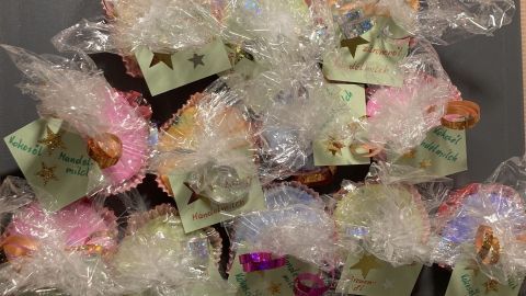 Bunte, selbstgemachte Seifen sind liebevoll verpackt und in Geschenkfolie auf einem Tisch angeordnet, bereit zum Verschenken.