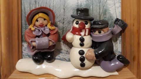 Eine Szene mit einer winterlichen Dekoration, die ein Mädchen und einen Schneemann in einem Rahmen zeigt.