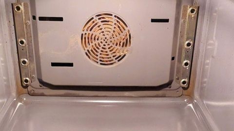 Der Innenraum eines Backofens zeigt eine saubere Oberfläche mit einem Ventilator in der Mitte, bereit für die Reinigung.