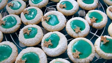 Kleine, runde Plätzchen mit grünem Zuckerguss und Keksen in einem Gitter, die festlich für den Pool-Trend 2023 dekoriert sind.