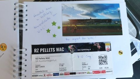Ein Fotobuch zeigt eine Eintrittskarte für ein WAC-Spiel mit Notizen und einem Bild des Stadions in der Lavanttal Arena.