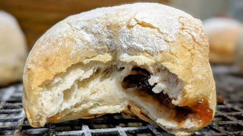 Süße Berliner mit fruchtiger Füllung liegen frisch gebacken auf einem Gitter, bereit zum Genießen.