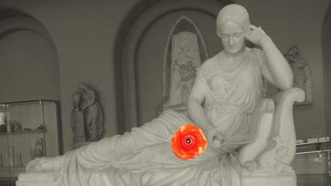 Eine Statue einer weiblichen Figur liegt entspannt, hält eine leuchtende Blume während sie in einem Museum ausgestellt ist.
