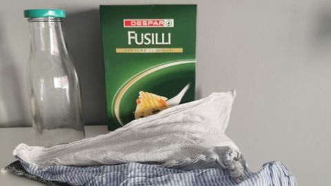 Ein Glasbehälter und eine Nudelpackung liegen auf einer weißen Fläche, um Müllvermeidung im Alltag zu unterstützen.