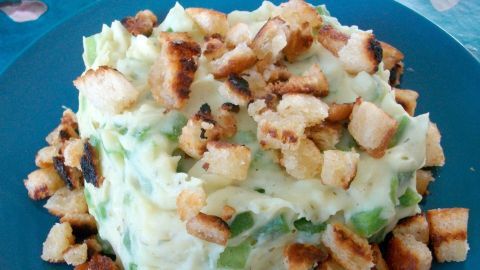 Kartoffelpüree wird in der Mitte eines blauen Tellers präsentiert, garniert mit knusprigen Croûtons.