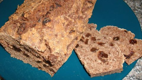Ein lautes, rustikales Birnenbrot liegt auf einem blauen Teller, daneben einige geschnittene Scheiben.