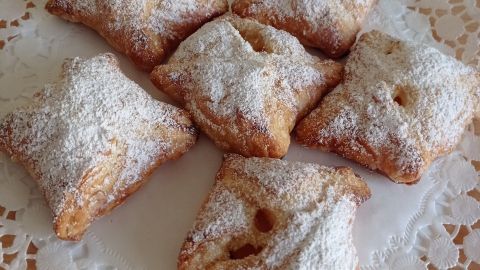 Blätterteig-Häppchen sind auf einem Spitzendeckchen arrangiert und leicht mit Puderzucker bestäubt.