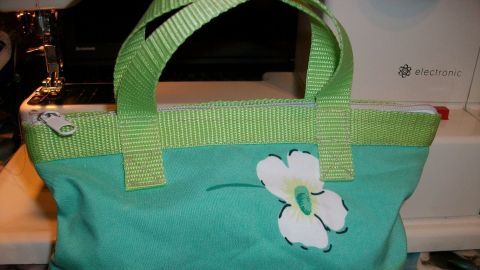 Eine farbenfrohe Kosmetiktasche steht auf einem Nähtisch und zeigt eine verspielte Blütenmusterung.