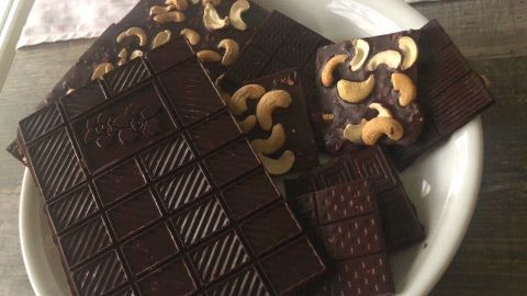 Eine Schüssel mit gesunder Schokolade, die auf einem Tisch steht, zeigt verschiedene Stücke mit Cashewkernen.