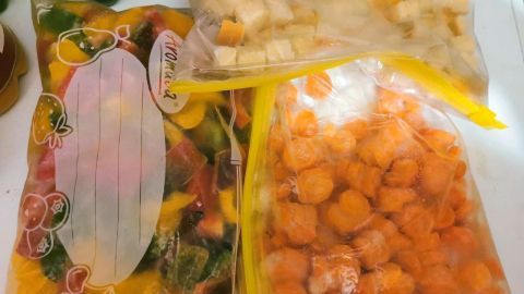 Bunte Tüten mit saisonalem Gemüse und Brotstücken sind in einem Kühlschrank sichtbar, bereit zum Einfrieren und Haltbar machen.