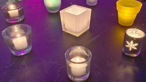 Wiederverwendbare Teelichte brennen in verschiedenen Gläsern auf einem dunklen Tisch, schaffen eine gemütliche Atmosphäre.