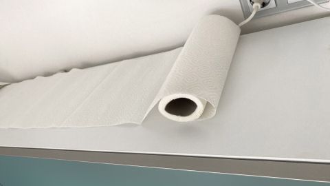 Ein Papiertuch liegt auf einem Küchenschrank, um Fett zu vermeiden, während Steckdosen daneben sichtbar sind.