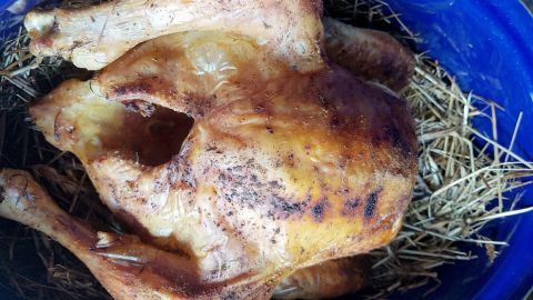Saftiges Huhn liegt in Heu, aromatisch zubereitet, in einer blauen Schüssel, bereit zum Servieren.
