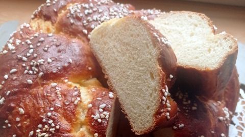 Ein Hefekranz liegt auf einer weißen Spitzenunterlage, eine Scheibe ist herausgeschnitten und sichtbar.