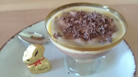 Eine Schale mit Schokomousse, garniert mit Eierlikör und Schokoladenraspeln, steht auf einem Teller neben einem Schokoladenhasen.