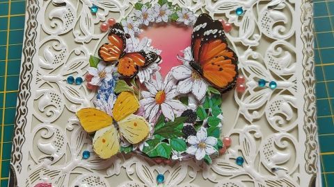 Die 3D Grußkarte zeigt bunte Schmetterlinge und Blumen, die auf einem kunstvollen, verzierten Hintergrund angeordnet sind.