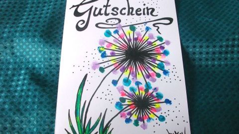 Eine kreative Gutscheinkarte zeigt bunte Blumen mit dem Text „Gutschein“ auf einem schimmernden Hintergrund.