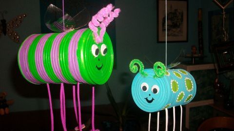 Bunte Insekten aus Konservendosen hängen in einem Raum, verziert mit Augen und Fühlern, kreativ und verspielt gestaltet.