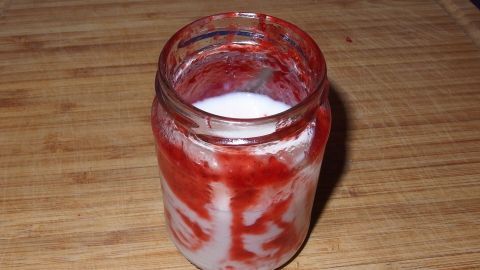 Marmeladenreste lecker verwerten: Marmeladenglas einfach mit Milch oder Joghurt füllen. Verschließen und kräftig schütteln. Fertig. Ein Glas mit restlicher Marmelade ist mit Milch gefüllt, auf einem Holzbrett platziert, bereit für einen Shake.
