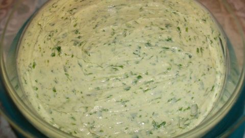 Eine grüne Petersilienbutter liegt in einer Schüssel und wirkt frisch und cremig, bereit zum Servieren.