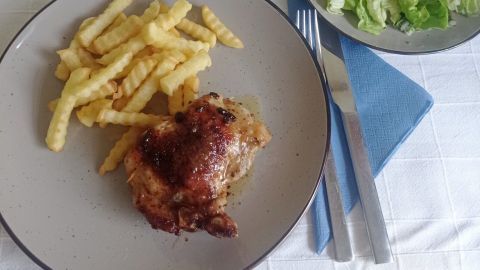 Auf einem Teller liegen knusprige Koteletts mit Pommes und einem frischen Salat in einem einfachen, hellen Ambiente.