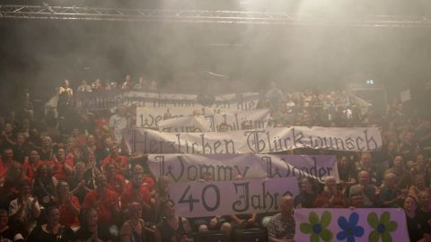 Großformatige, selbstgemachte Banner mit Glückwünschen für einen 40. Geburtstag werden von einer jubelnden Menge gehalten.