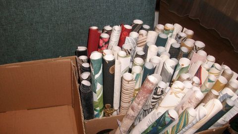 In einer großen Pappschachtel stehen viele dekorative Tapetenrollen. Sie warten darauf, für DIY Glückwunschröllchen verwendet zu werden.