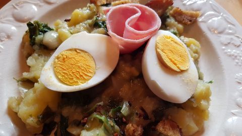 Endivien-Kartoffelstampf mit gekochtem Ei und Schinken, serviert auf einem Teller; das Gericht kombiniert Kartoffelstampf mit Endivien.
