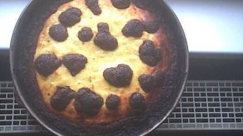 Ein runder, gebräunter russischer Zupfkuchen liegt auf einem Gitter, einige Stellen sind dunkel und verbrannt.