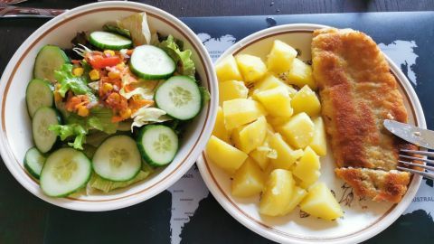 Knusprig paniertes Rotbarschfilet mit Salzkartoffeln und gemischtem Salat als Beilage serviert.