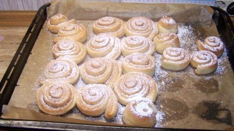 Frisch gebackene Zimt-Nuss-Schnecken: Perfekt für einen gemütlichen Nachmittag. Der Artikel erklärt das köstliche Rezept dieser Zimt-Leckereien, die mit Puderzucker bestreut auf dem Blech verlockend duften.