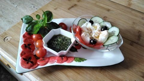 Die Burrata mit der Gabel ausreißen. Meersalz und ein gutes Olivenöl darübergeben. Dazu schwarze Oliven, frische süße kleine Tomaten und Bärlauch-Pesto.
