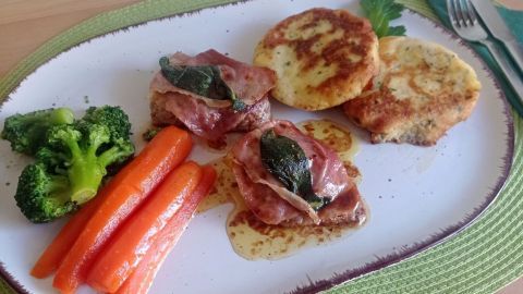 Kalbsschnitzel Saltimbocca mit Salbei und Schinken, serviert mit buntem Gemüse und Kartoffeltalern. Italienischer Genuss auf dem Teller.