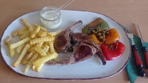 Angerichtet werden pro Person drei gebratene Koteletts, die Paprika-Viertel und Pommes Frites sowie Aioli.