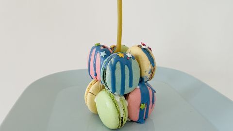 Mini-Geburtstagskuchen mit Macarons selber machen: Einfach mit Zuckerguss und Kerze verzieren.
