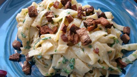Die originale Tagliatelle Carbonara so angerichtet, dass die Speck-Grieben als Topping darauf gegeben wurden, so bleiben sie knusprig.