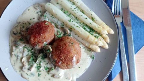 Angerichtet werden die Geflügelhackbällchen auf der Champignonsoße, mit dem Spargel und neuen Kartoffeln.