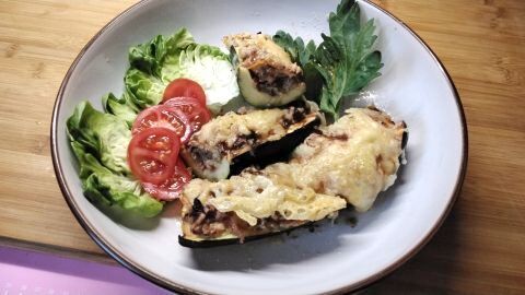 Schnelles Airfryer-Rezept: Gefüllte Zucchini mit Käse überbacken, angerichtet mit frischem Salat und Tomaten.